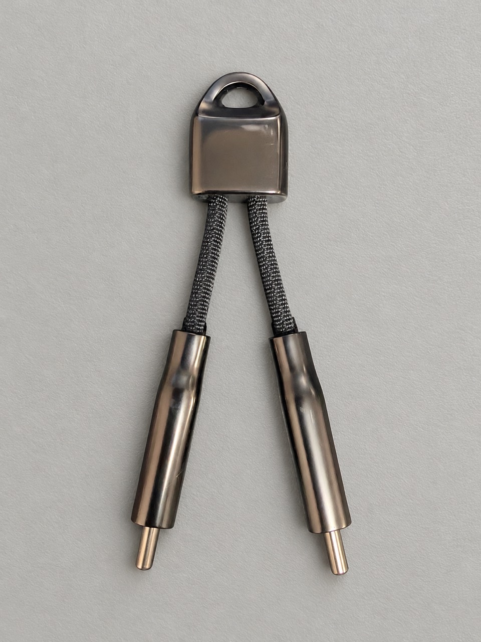 両端を離したNOMAD ChargeKey。短い編み込みケーブルと金属のUSB-Cコネクター、上部のリング穴
