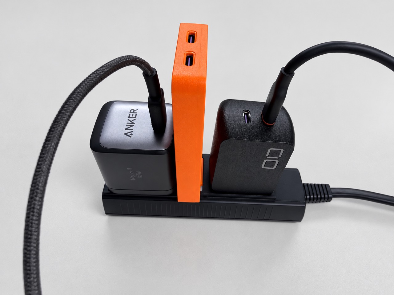 電源タップの両隣の充電器の間に差せた、手持ちのオレンジ色SLIM DUO II 65W版
